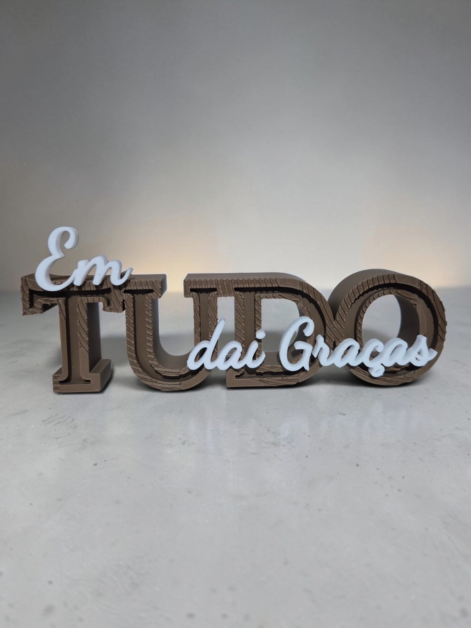Letreiro 3D Em Tudo Dai Graças em marrom com detalhes brancos sobre fundo azul-claro
